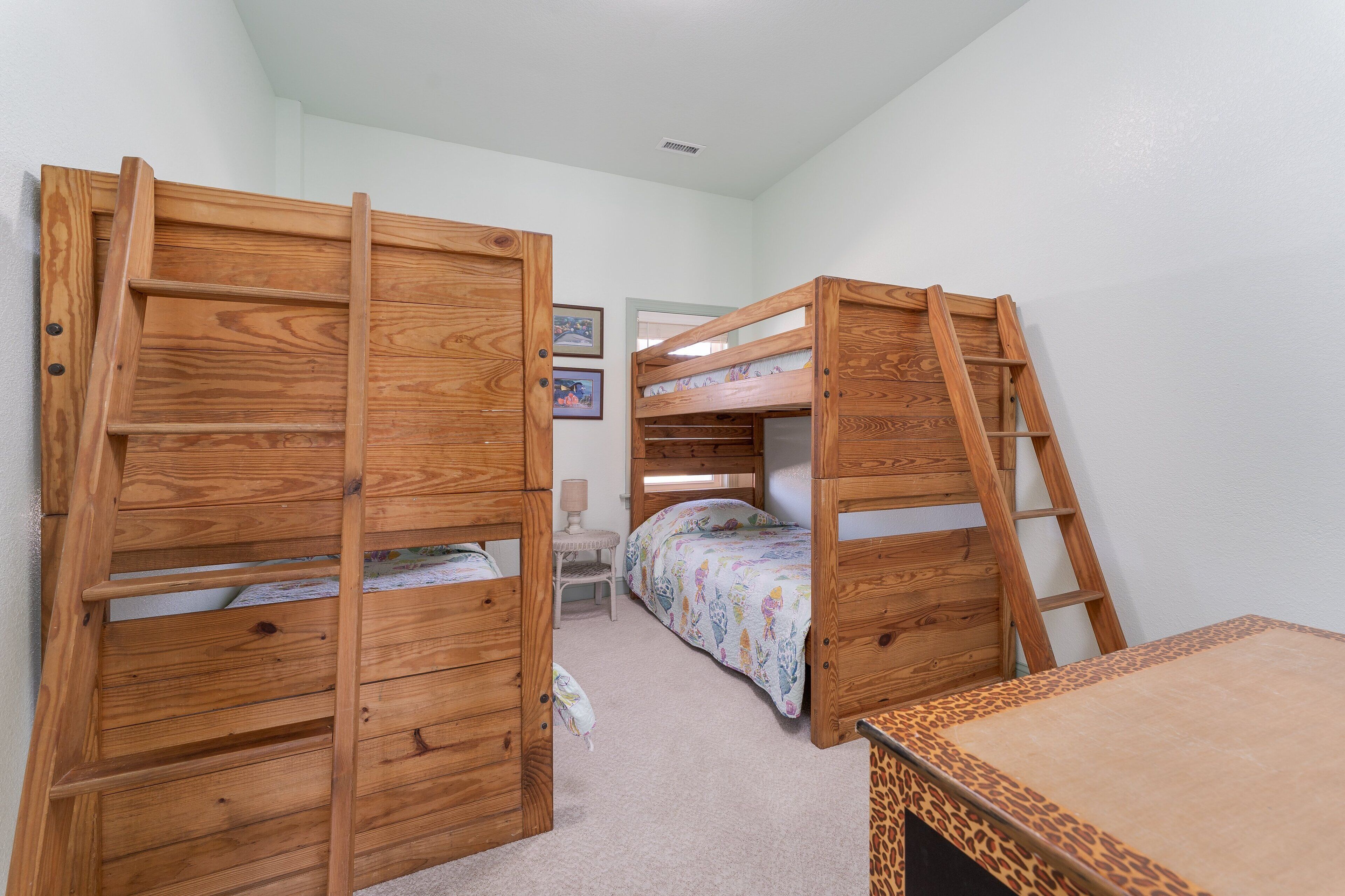 A room with two bunk beds, a small desk, and a chair.