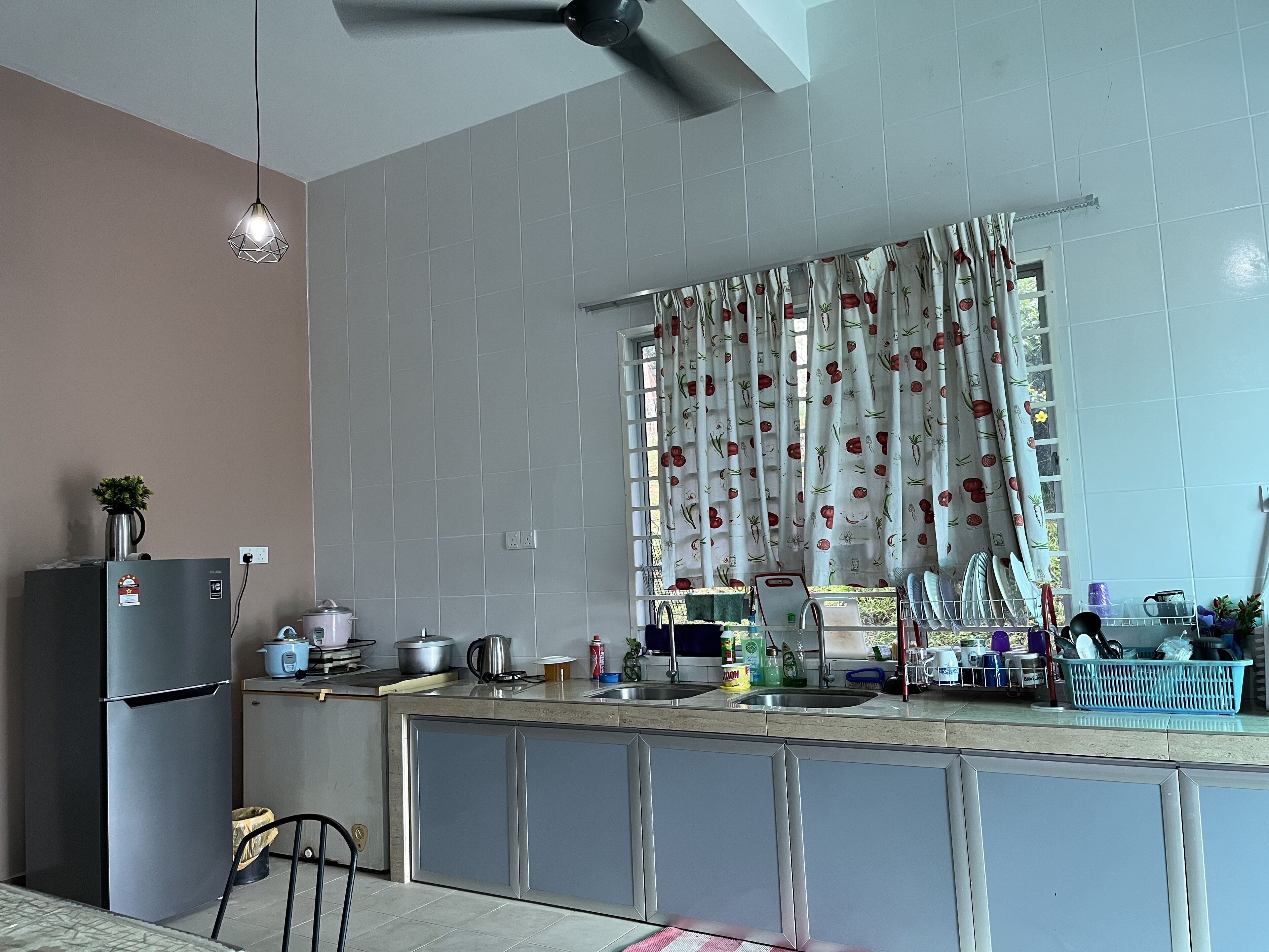 A kitchen with a refrigerator, stove, sink, and various kitchen items.