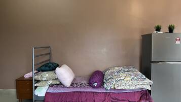 A bedroom with a bed, a nightstand, a dresser, and a refrigerator.