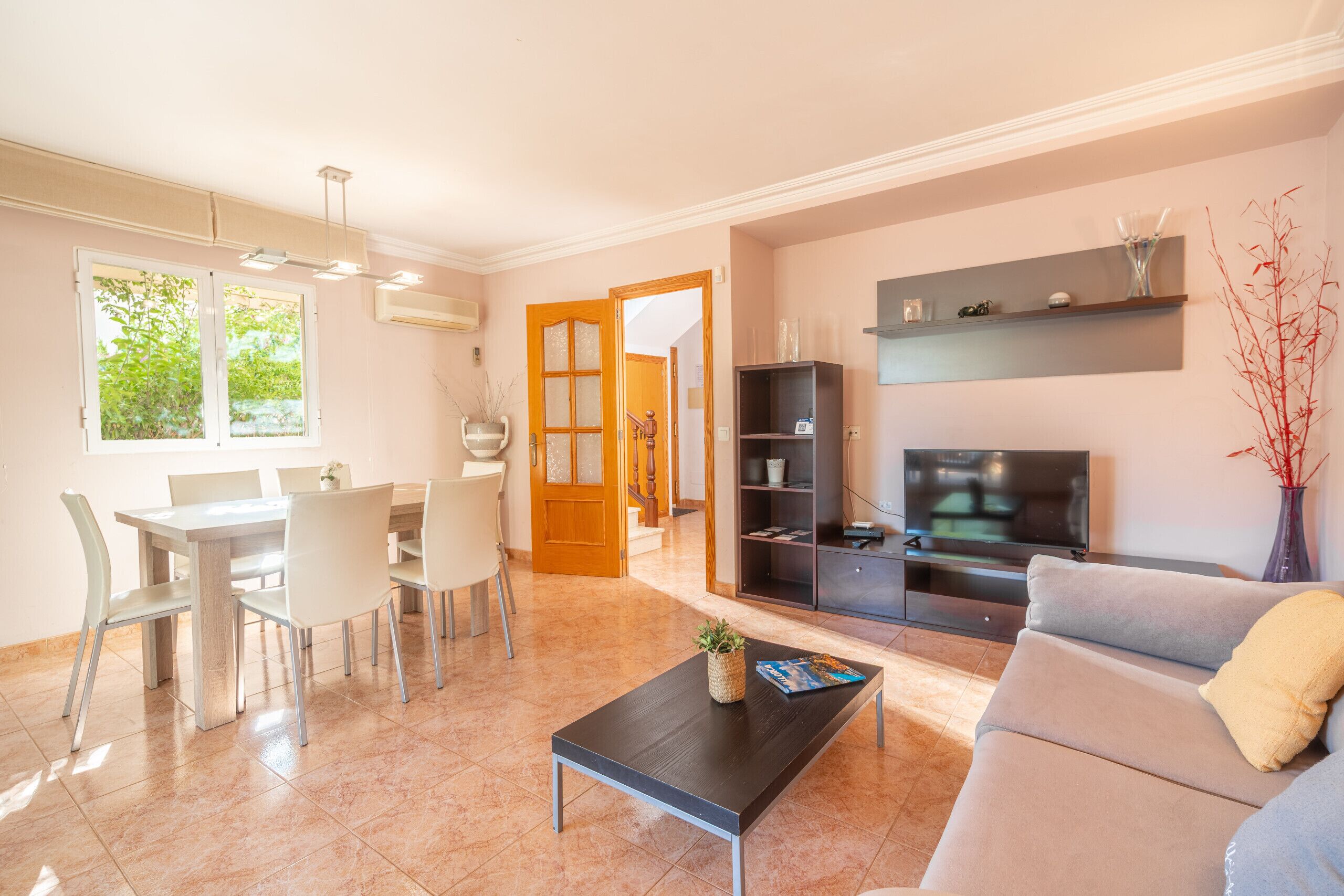 A modern living room with a sofa, coffee table, TV, and dining area with chairs and a table.