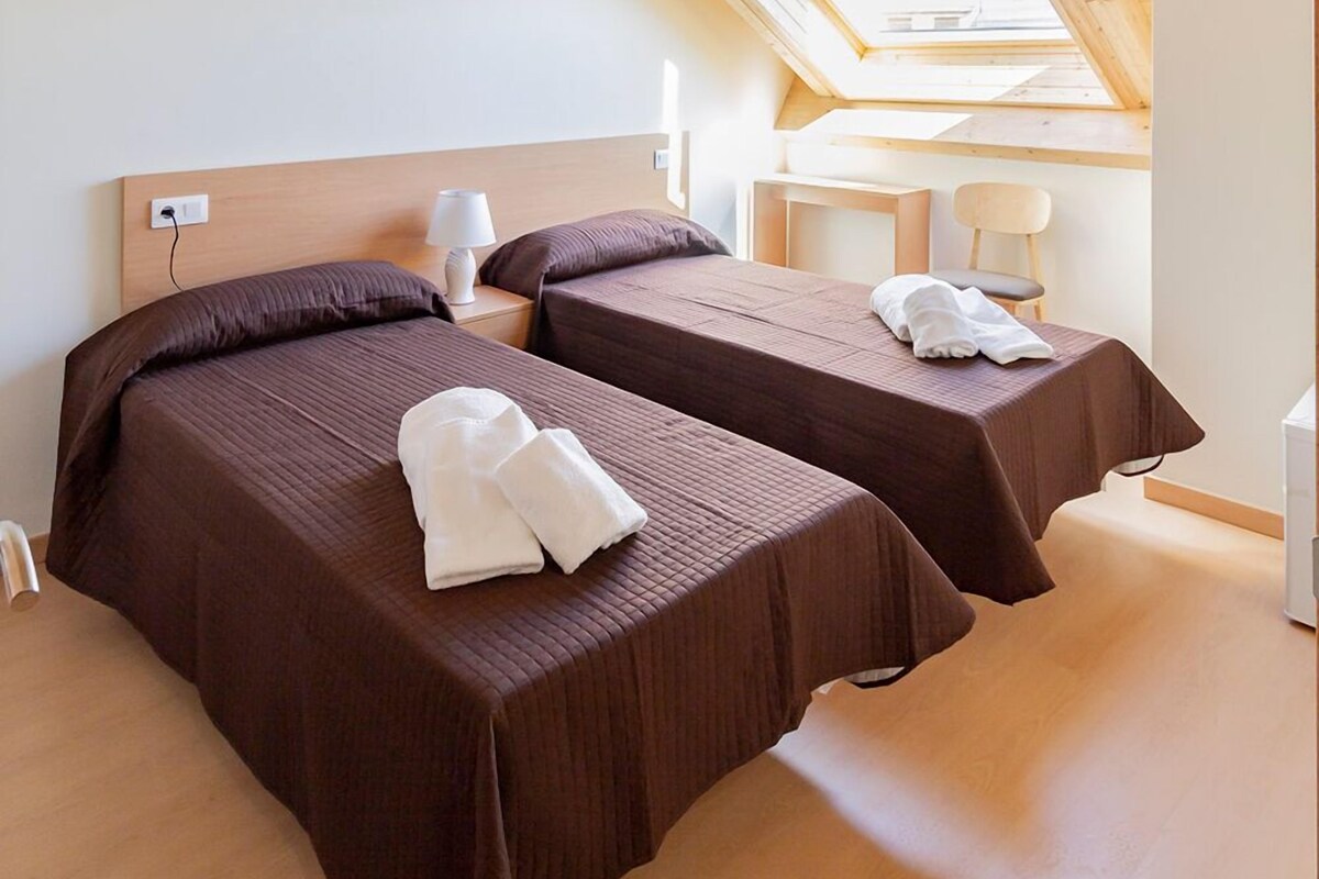 Un dormitorio con dos camas, un tragaluz y techo de madera.