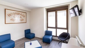 Una sala de estar moderna con sofás azules, una mesa de centro blanca y un televisor montado en la pared.