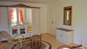 Ein Zimmer mit einem Bett, einem Schrank, einem Spiegel und einem Korbstuhl.