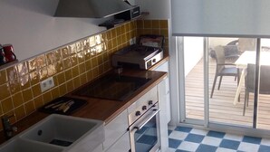 Een keuken met een geruit vloertje, een spoelbak, een fornuis en een raam met uitzicht op een terras.