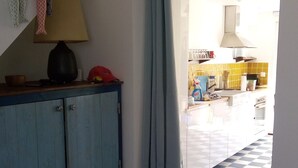 Een kamer met een geruite vloer, een blauwe kast, een lamp en een stoel met een bloemenkussen.
