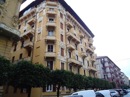 Un edificio de varios pisos con detalles arquitectónicos ornamentados, incluyendo balcones y molduras decorativas.