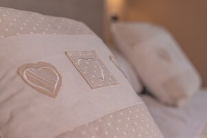 Un cojín con diseños bordados en forma de corazón y rectángulos.