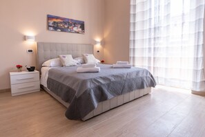 Une chambre à coucher moderne avec un grand lit, des tables de chevet, une commode et un tableau au mur.