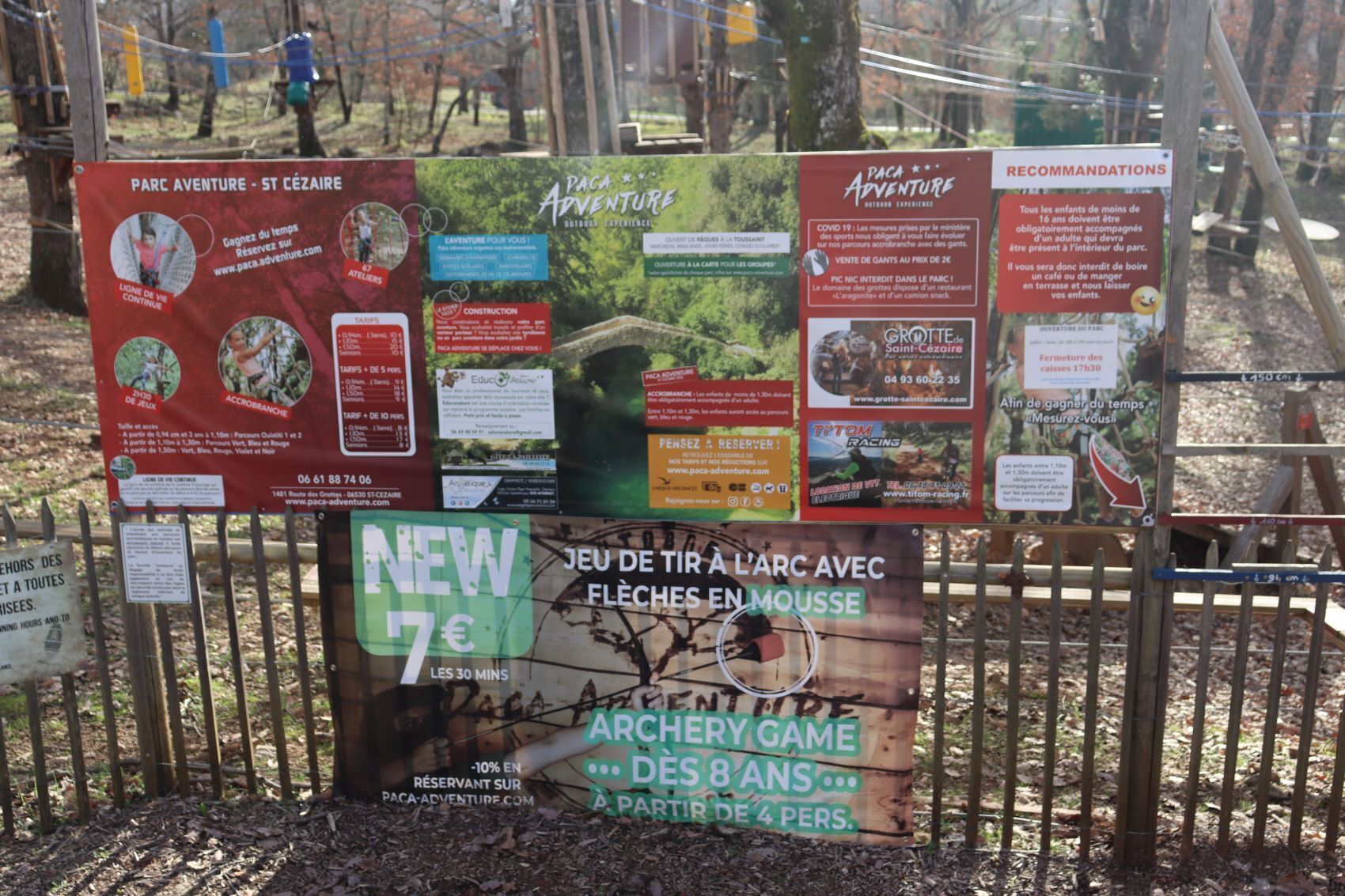 Ein Schild mit verschiedenen Informationen zum Parc Adventure – St. Cezaire, darunter Aktivitäten, Preise und Empfehlungen.