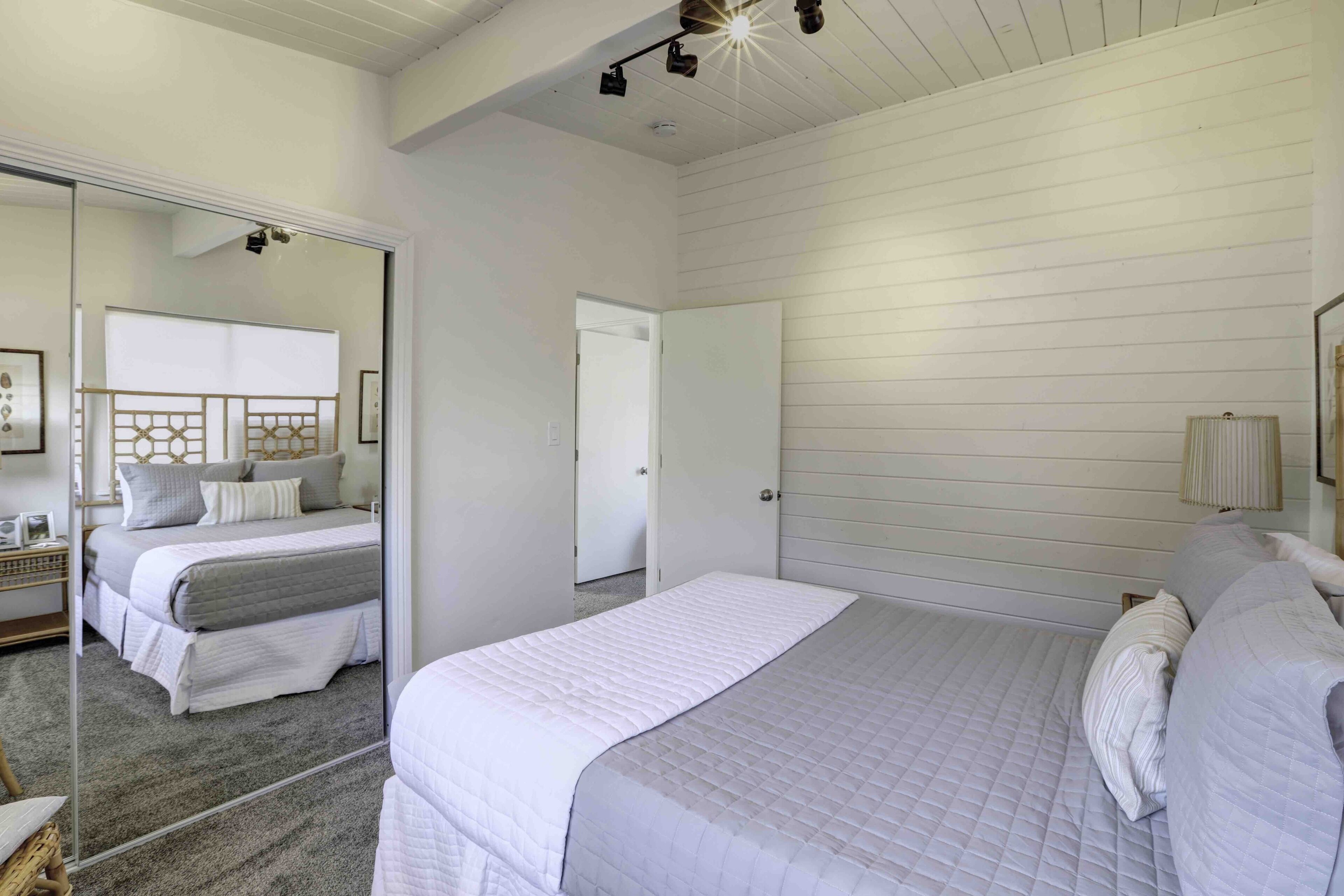 Un dormitorio con una cama grande, un espejo y una puerta que da a otra habitación.