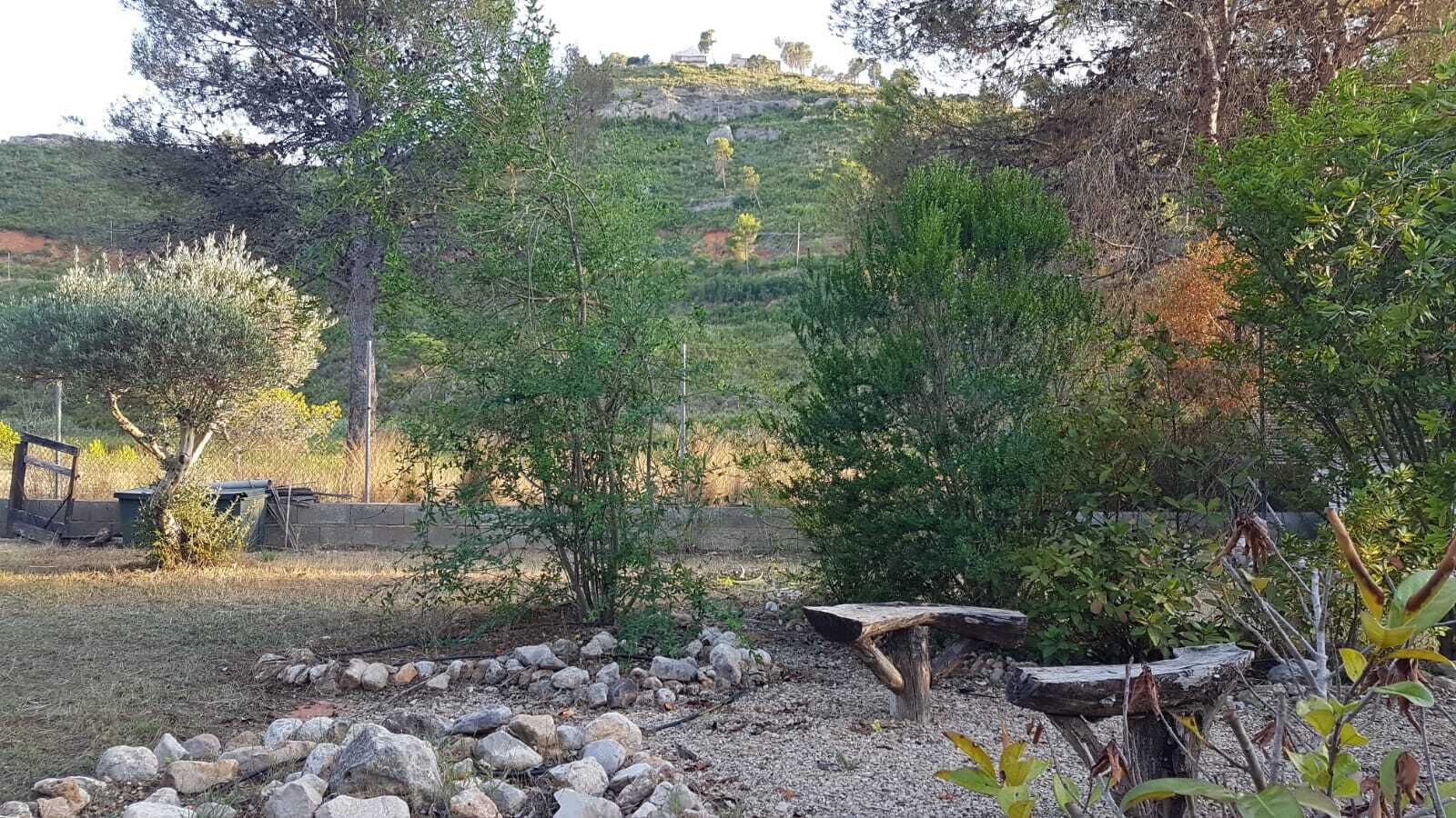 Un jardin avec un banc en bois, des rochers et des arbres.