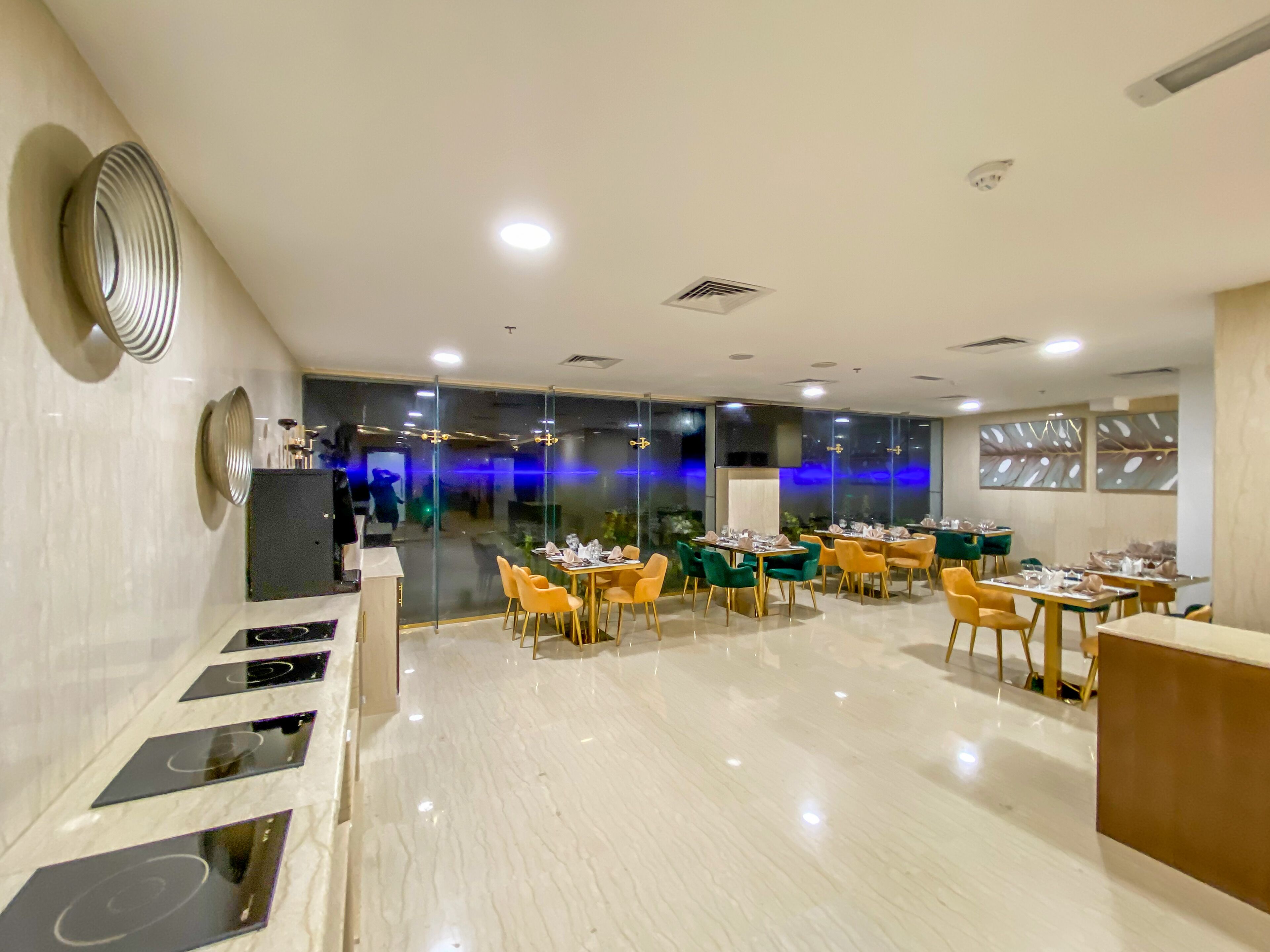 A modern restaurant with a clean, polished floor and a variety of seating options including yellow and green chairs.