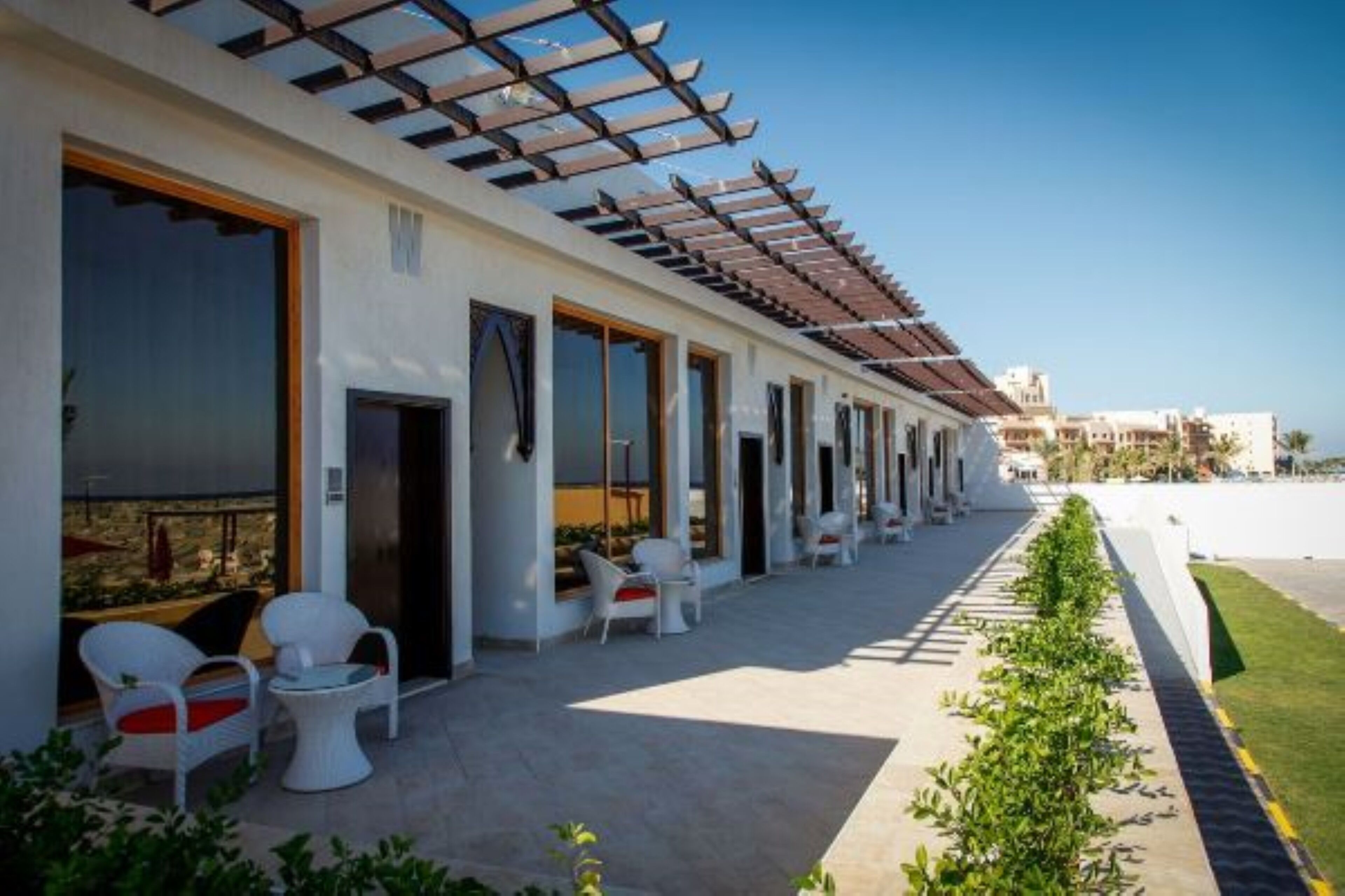 A hotel with a covered outdoor seating area, large windows, and a view of the surrounding buildings.