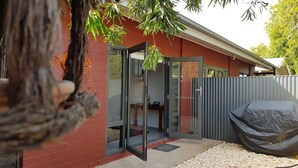 A modern house with a red brick exterior, a glass door entrance, and a covered barbecue area.