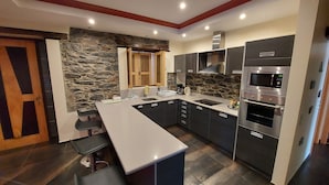 A modern kitchen with dark cabinets, a white countertop, and a stone accent wall.