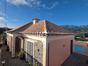 Una casa pequeña con techo de tejas, paredes de piedra y una piscina.