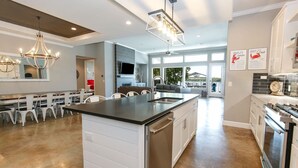 A modern kitchen with a central island, built-in appliances, and a dining area with white chairs. - Bud Lane Lakeside | Concierge Services (Kingsland)