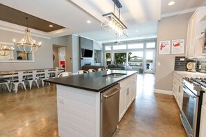 Een moderne keuken met een centraal eiland, inbouwapparatuur en een eethoek met witte stoelen.