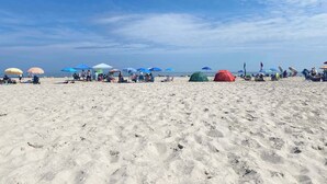 A sandy beach with several tents and umbrellas. - 1 BR Suite/1st Floor / East Side of Beach Block (Ocean City)