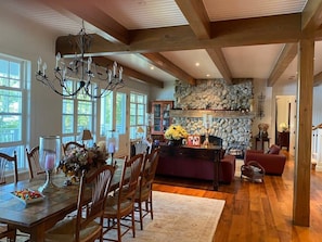 A spacious dining area with a wooden table and chairs, a chandelier, and a stone fireplace. - Muskoka Point of View! (Bracebridge)