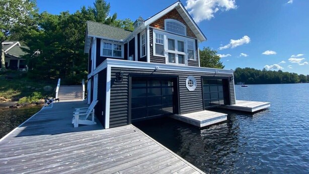 A house on a dock extending into a lake, with a garage and a covered area.