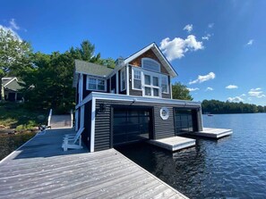 A house on a dock extending into a lake, with a garage and a covered area. - Muskoka Point of View! (Bracebridge)