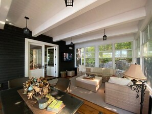 A spacious living area with a large window, a dining table with a vase of flowers, and a cozy seating arrangement. - Muskoka Point of View! (Bracebridge)