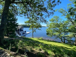 A lakeside cabin with a dock, surrounded by trees and greenery.