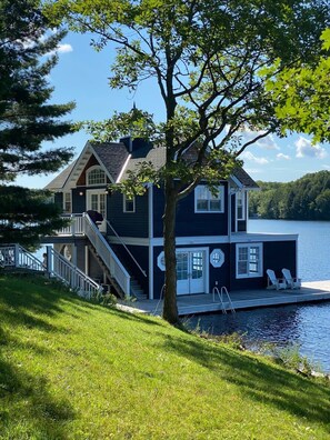 A two-story house with a dock, a staircase, and a view of the lake.