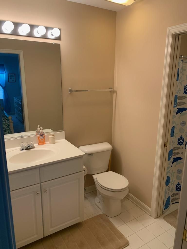 Een badkamer met een witte wastafel, toilet en douchegordijn met visjes.