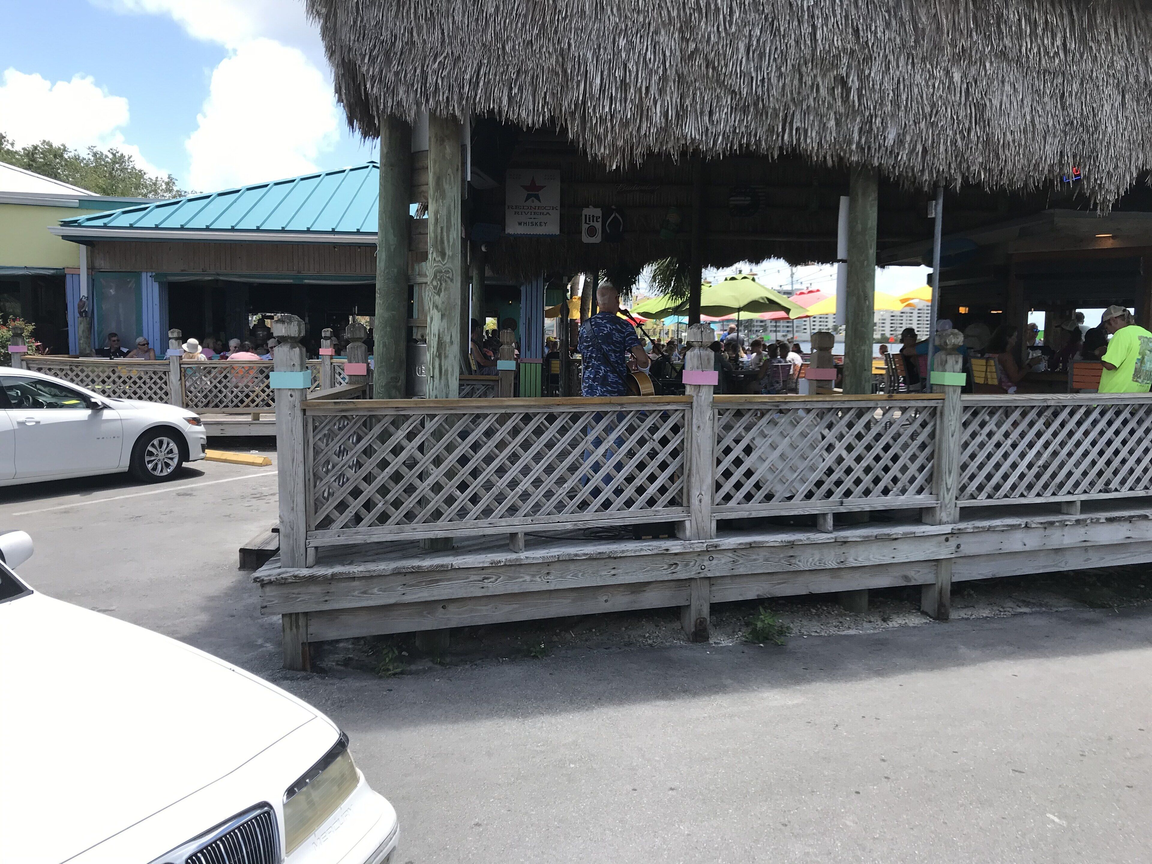 A wooden structure with a thatched roof, possibly a restaurant or bar, with a sign indicating it serves whiskey.