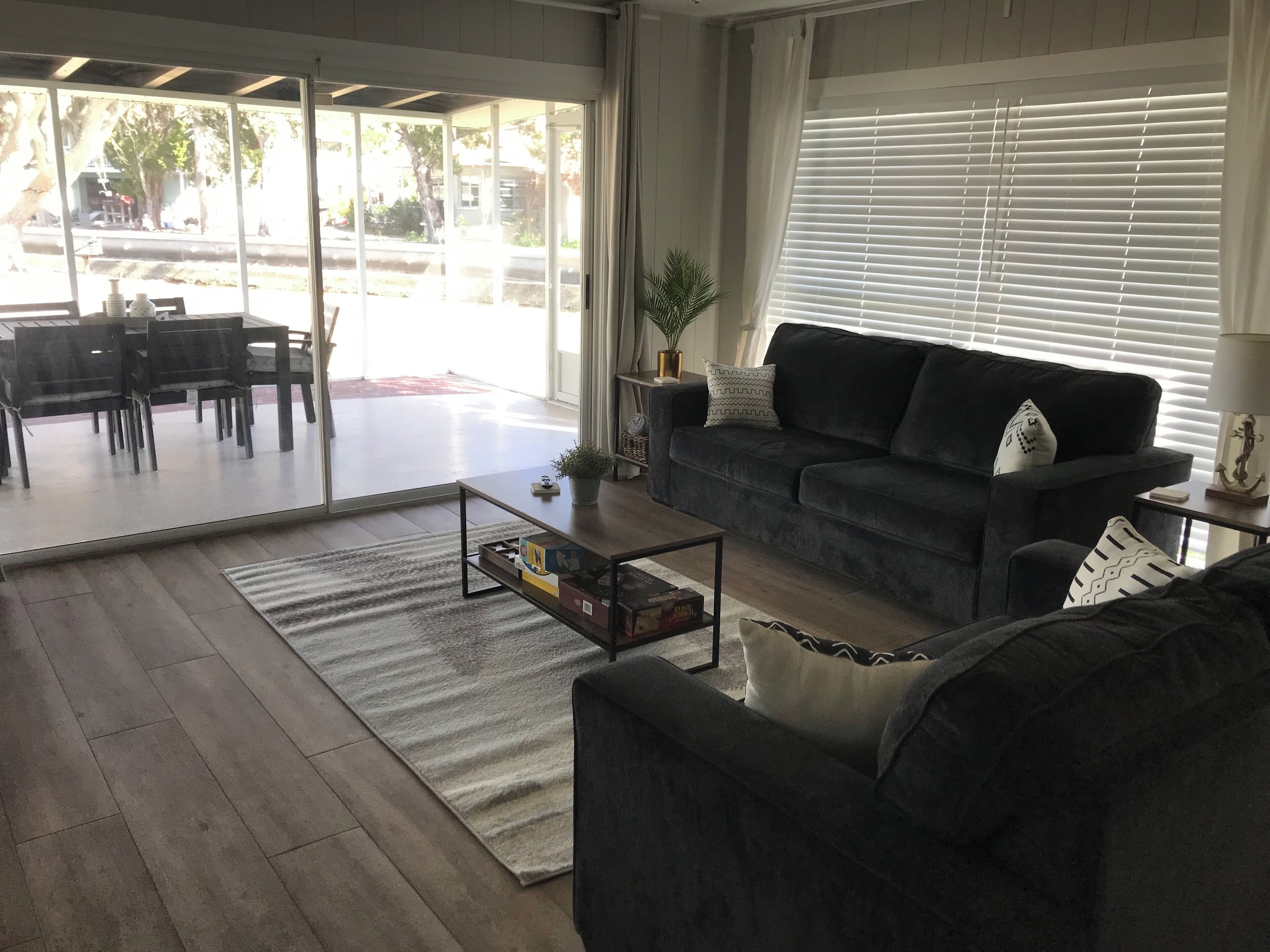 Un saló amb un sofà gris fosc, una taula de centre i una zona menjador amb cadires i una taula.