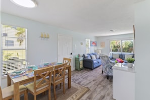 A dining area with a wooden table set for four, a blue sofa, and a kitchen counter.