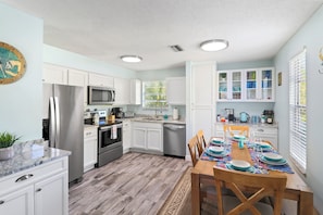 A modern kitchen with white cabinets, stainless steel appliances, and a dining area set for six.