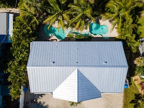 Une vue aérienne d’un bâtiment doté d’un toit plat, entouré de palmiers et d’une piscine.