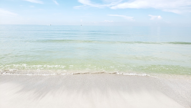 Een strand met helder water en een rustige zee.