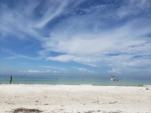 A beach with white sand and calm water.