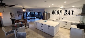Una cocina moderna con una isla grande, armarios blancos y un letrero que dice "MOON BAY" en la pared.