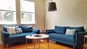 A living room with two blue sofas, a round coffee table, and a floor lamp.