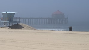 Una playa con una torre de salvavidas y un muelle que se adentra en el agua.