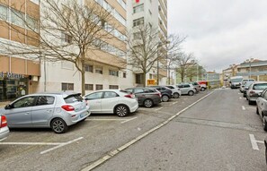 En parkeringsplads med flere biler parkeret langs gaden, ved siden af en bygning med et skilt, der siger 'el Mestre'.