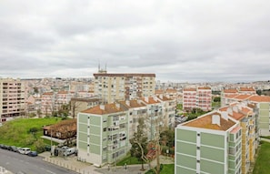 Zona residencial com edifícios altos, uma rua e uma área ajardinada com árvores.