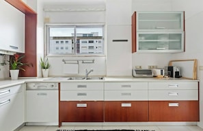 A modern kitchen with a built-in oven, a sink, and a window with a view of buildings. - Bright & Spacious Three-Bed Apartment in Lisbon (Lisboa)
