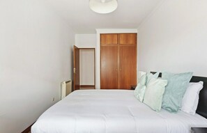 Een slaapkamer met een bed, een garderobe en een radiator.