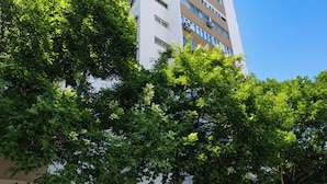 A multi-story building with a white facade, a visible entrance, and a staircase leading to the ground floor. - Bright & Spacious Three-Bed Apartment in Lisbon (Lisboa)