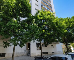 A multi-story building with a white facade, a visible entrance, and a staircase leading to the ground floor. - Bright & Spacious Three-Bed Apartment in Lisbon (Lisboa)