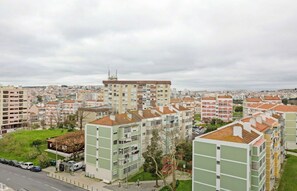 A residential area with multi-story buildings, a road, and a grassy area with trees. - Bright & Spacious Three-Bed Apartment in Lisbon (Lisboa)