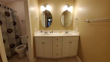 A bathroom with a double sink vanity, a toilet, and a shower curtain with floral patterns.
