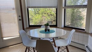 A dining area with a round table, four white chairs, and a potted plant. - PERFECT DESERT OASIS~lake~jet ski~boat (Truth or Consequences)