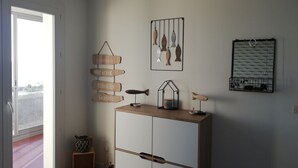 A room with a wardrobe, a hanging fish decoration, a wall-mounted fish art, and a basket on the floor. - Magnifique T3 vue MER, Port de St Cyprien plage (Saint-Cyprien)